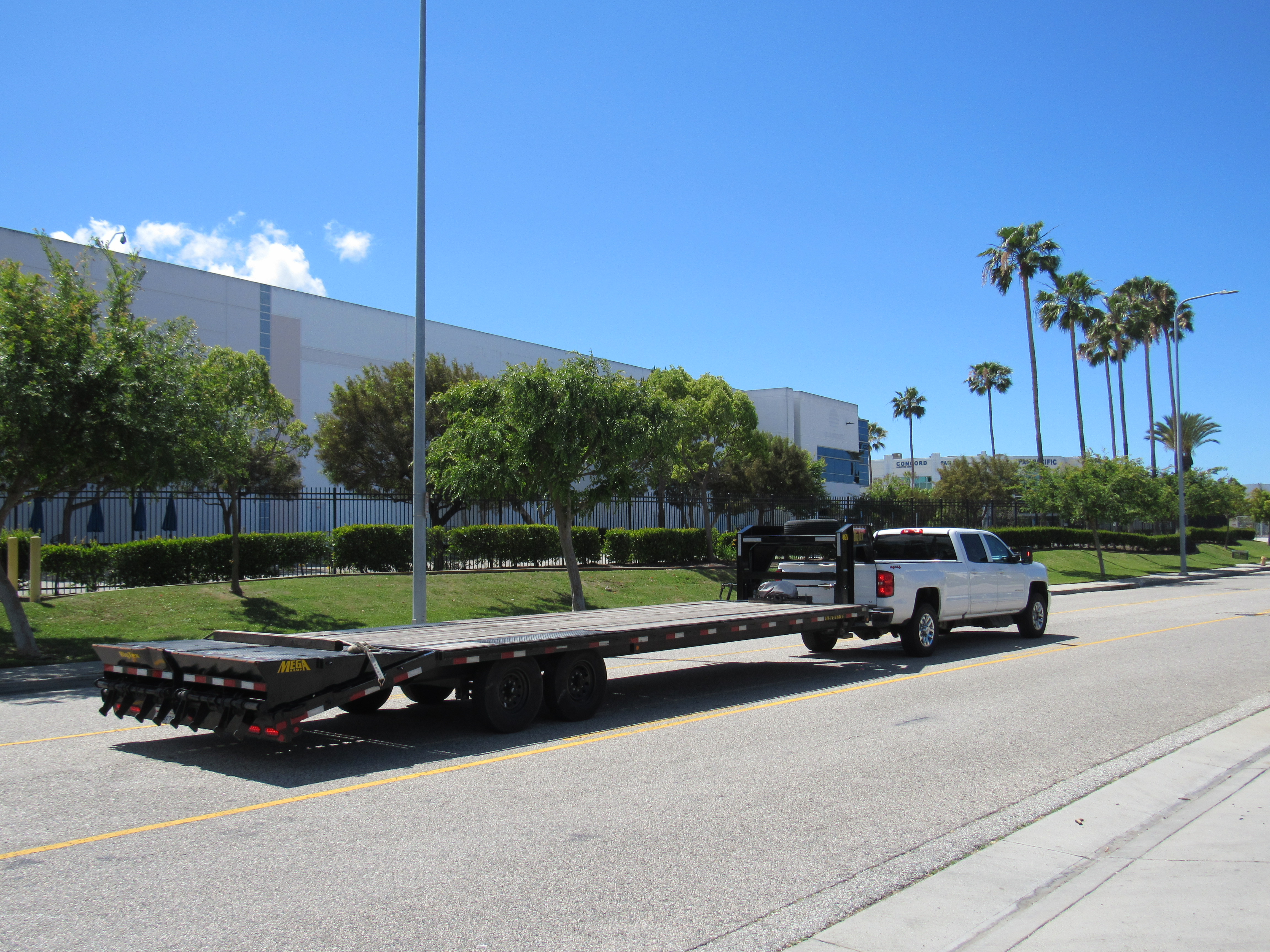 Full view of the Silverado and Big Tex gooseneck flatbed trailer from the rear on a commercial street